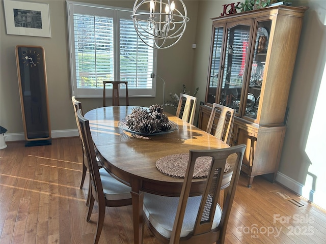 dining room with an inviting chandelier, light wood-style floors, and baseboards