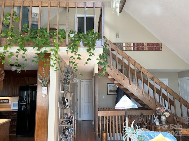 staircase featuring visible vents, wood finished floors, and vaulted ceiling