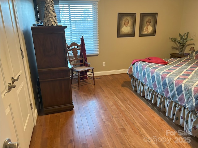 bedroom with baseboards and hardwood / wood-style flooring