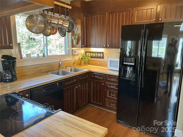 kitchen with black appliances, wood finished floors, and a sink