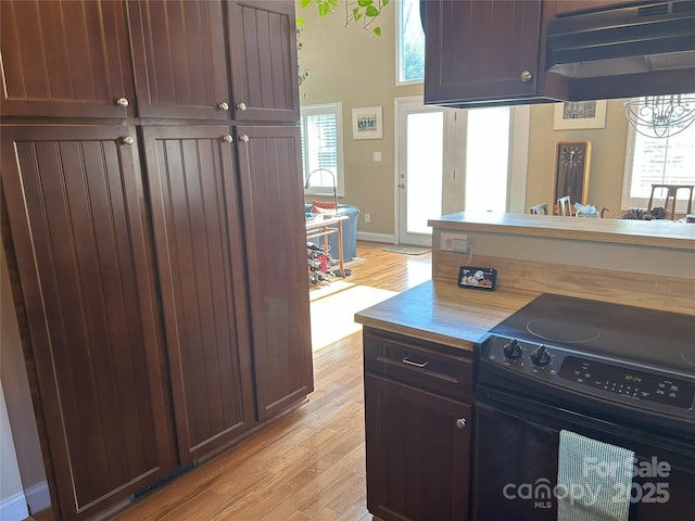 kitchen with butcher block countertops, light wood-style flooring, black range with electric cooktop, and baseboards