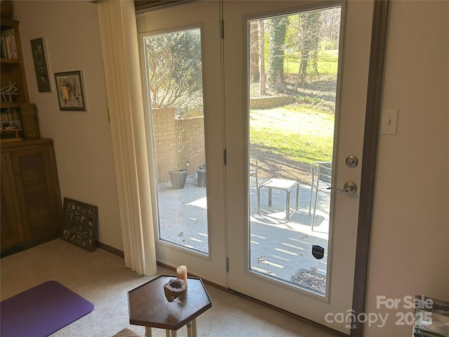 entryway with baseboards and light carpet