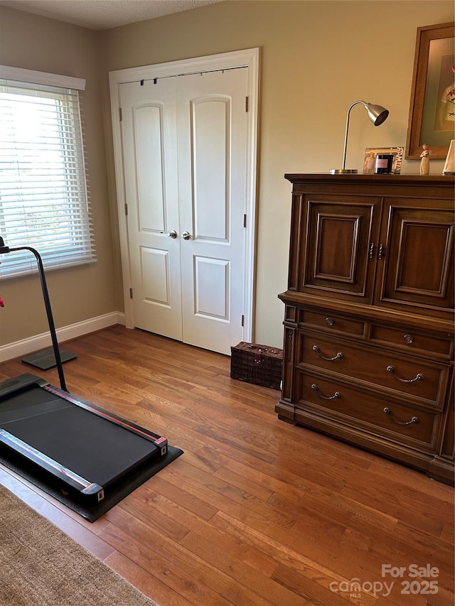 exercise area with light wood-type flooring and baseboards