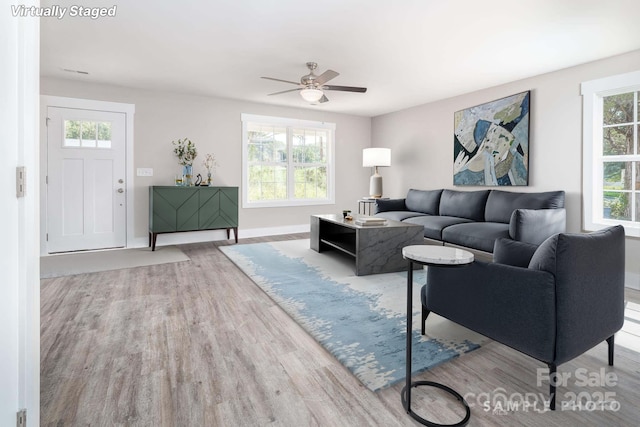 living area featuring baseboards, wood finished floors, and ceiling fan