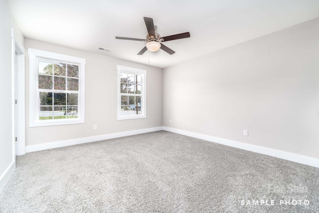 carpeted spare room with ceiling fan, baseboards, a healthy amount of sunlight, and visible vents