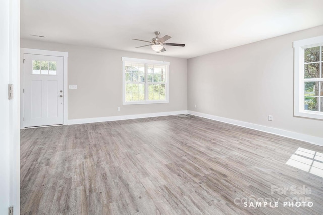 unfurnished living room with plenty of natural light, a ceiling fan, and wood finished floors