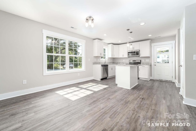kitchen featuring wood finished floors, white cabinetry, baseboards, and stainless steel appliances