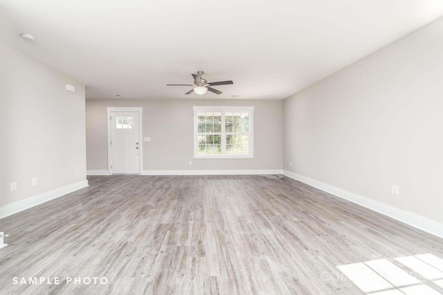 unfurnished living room with ceiling fan, baseboards, and wood finished floors