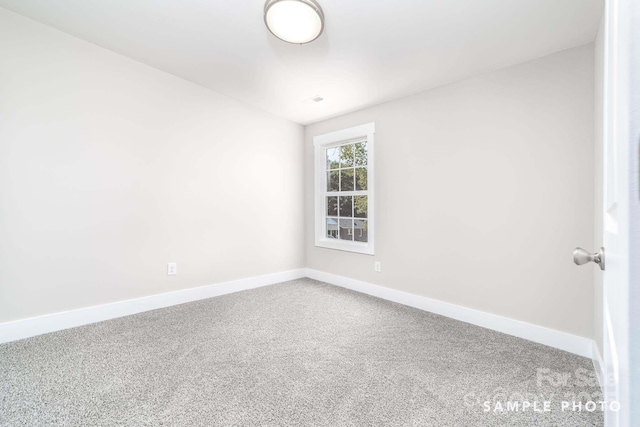carpeted spare room featuring baseboards