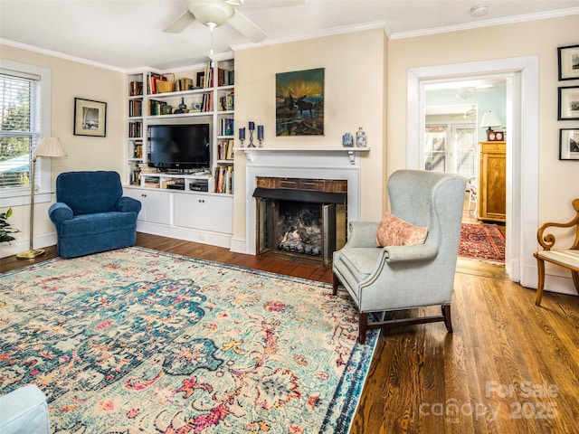 living room featuring a fireplace with flush hearth, crown molding, and wood finished floors