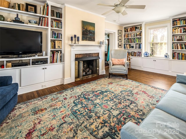 living area featuring ornamental molding, a fireplace, wood finished floors, and a ceiling fan