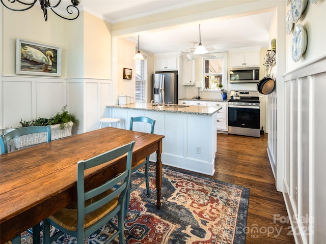 kitchen featuring appliances with stainless steel finishes, ornamental molding, white cabinetry, a sink, and a peninsula