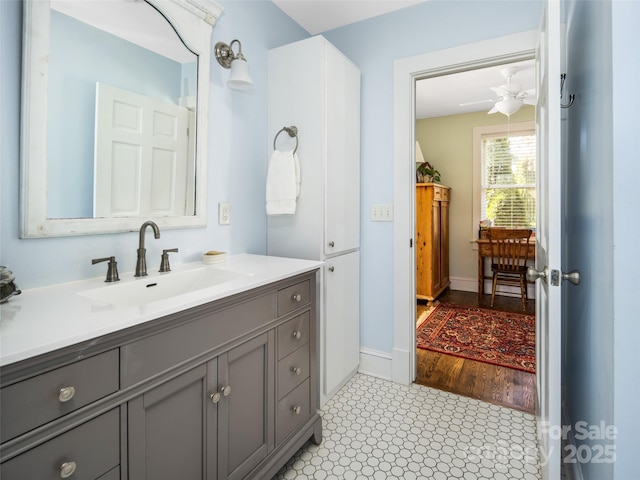 bathroom featuring ceiling fan, baseboards, and vanity