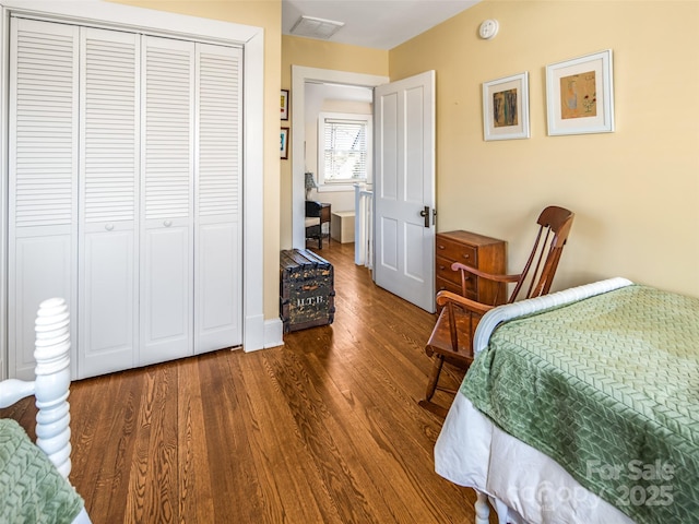 bedroom with a closet, visible vents, and wood finished floors