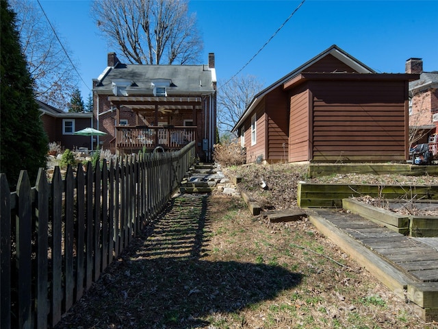 view of side of property featuring a chimney, fence, and a vegetable garden