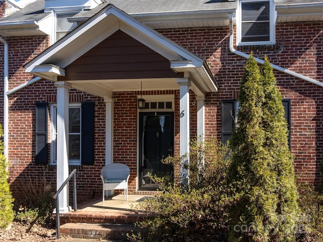 view of exterior entry with covered porch and brick siding