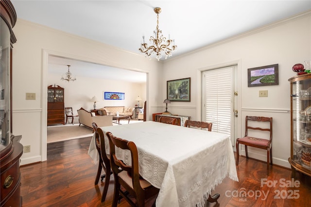 dining area with dark wood-style flooring, crown molding, baseboards, and an inviting chandelier