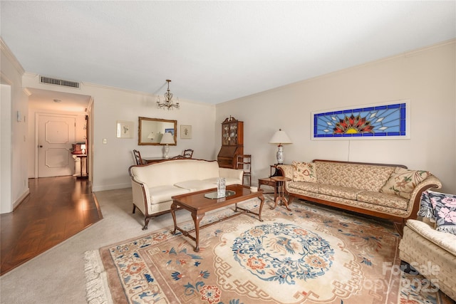 living room featuring crown molding, a notable chandelier, visible vents, carpet flooring, and baseboards