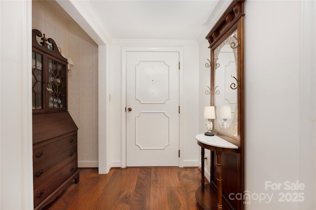 doorway to outside featuring crown molding, baseboards, and wood finished floors