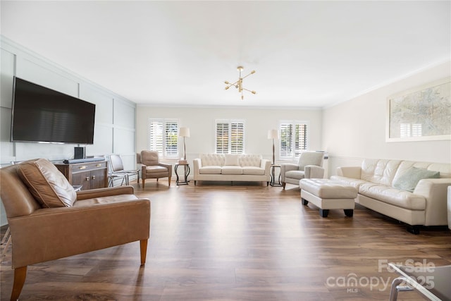 living room with dark wood-style floors, ornamental molding, and a notable chandelier