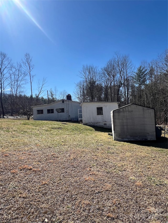 back of property featuring crawl space, an outdoor structure, and a yard