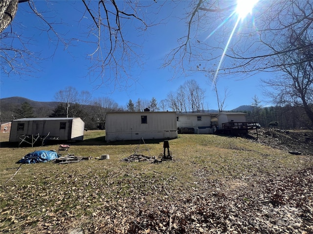 exterior space featuring crawl space, a mountain view, a lawn, and an outdoor structure