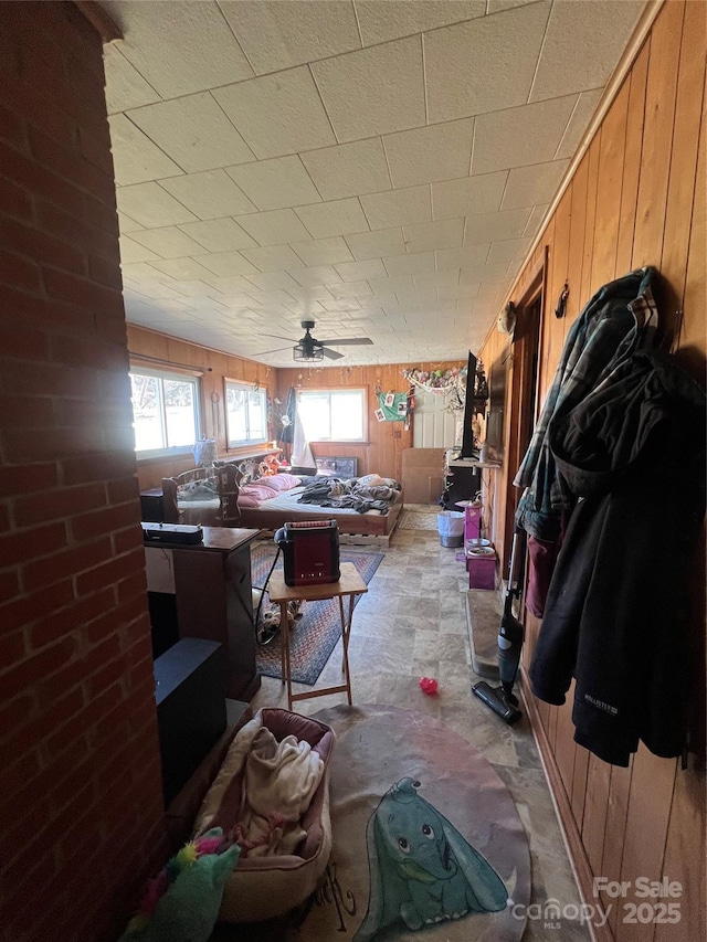 miscellaneous room featuring a ceiling fan and wood walls