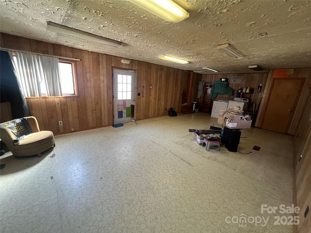 misc room featuring washing machine and dryer, wooden walls, and a textured ceiling