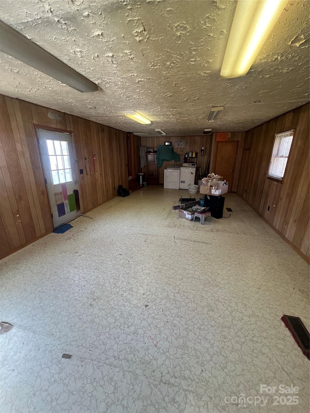 interior space featuring wooden walls, washer and clothes dryer, and a textured ceiling