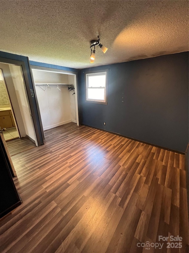 unfurnished bedroom featuring a textured ceiling, a closet, and wood finished floors