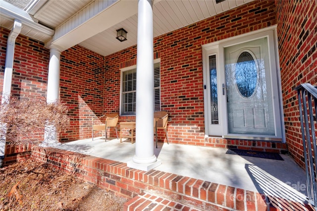 property entrance with covered porch and brick siding