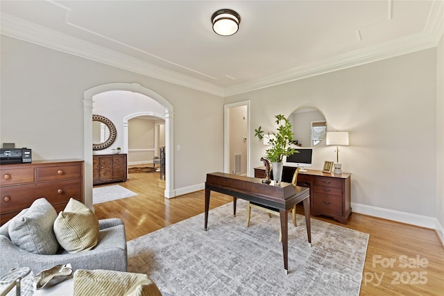 home office featuring arched walkways, baseboards, crown molding, and light wood-style floors