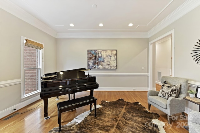 living area with visible vents, baseboards, crown molding, and light wood finished floors