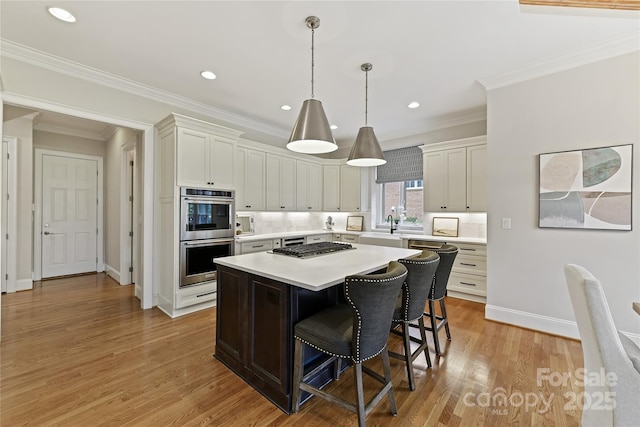 kitchen with a breakfast bar area, light countertops, light wood-style floors, appliances with stainless steel finishes, and a center island