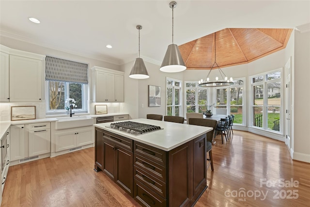 kitchen with dark brown cabinets, a breakfast bar area, decorative backsplash, stainless steel gas stovetop, and a sink