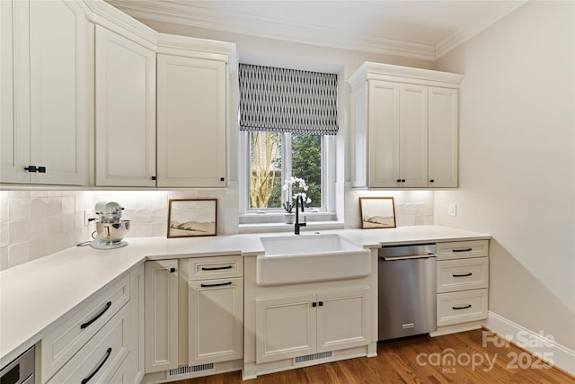 kitchen featuring visible vents, ornamental molding, a sink, backsplash, and wood finished floors