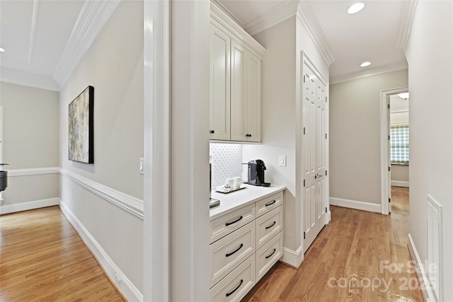 hallway featuring light wood-type flooring, visible vents, ornamental molding, recessed lighting, and baseboards