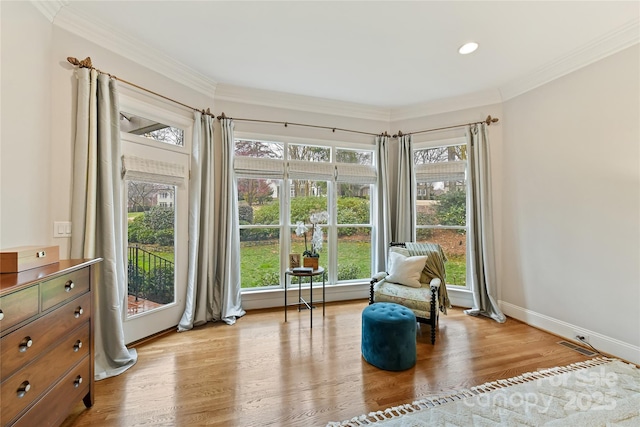 sitting room with light wood-type flooring, baseboards, and a healthy amount of sunlight