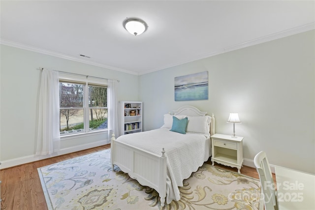 bedroom with visible vents, wood finished floors, baseboards, and ornamental molding