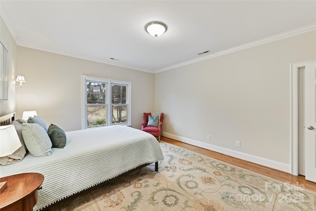 bedroom featuring visible vents, baseboards, wood finished floors, and ornamental molding