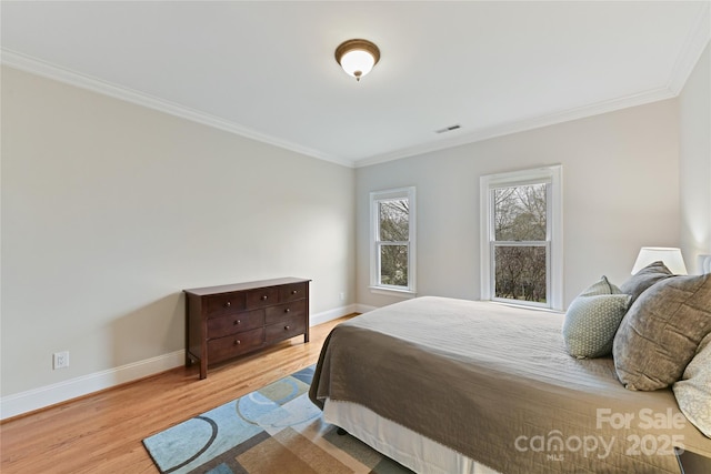 bedroom featuring visible vents, ornamental molding, baseboards, and wood finished floors