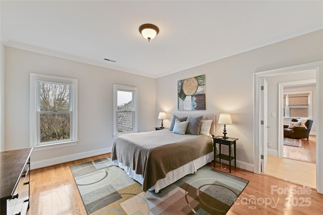 bedroom with crown molding, baseboards, and wood finished floors