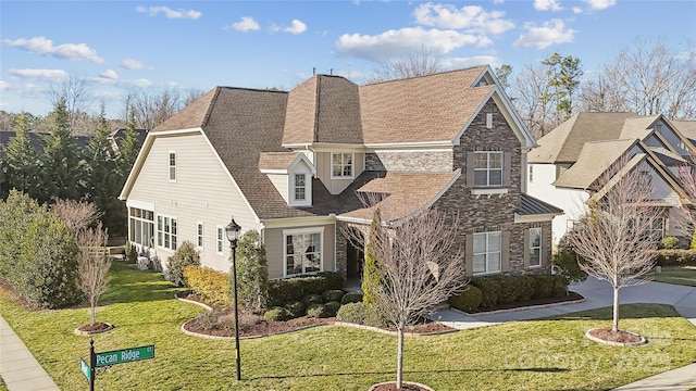 view of front facade featuring driveway, stone siding, and a front yard