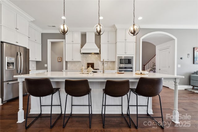 kitchen with dark wood-style floors, appliances with stainless steel finishes, white cabinets, and custom range hood