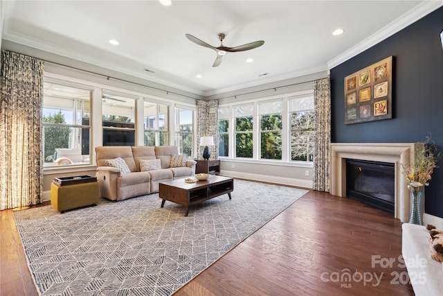 living area featuring a glass covered fireplace, crown molding, recessed lighting, and wood finished floors