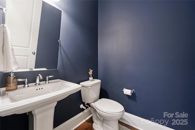 bathroom with baseboards, a sink, and toilet