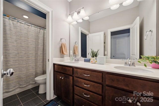 full bathroom featuring double vanity, tile patterned flooring, a sink, and toilet