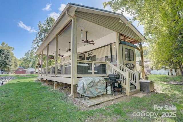 exterior space with fence, a deck, a ceiling fan, and a yard