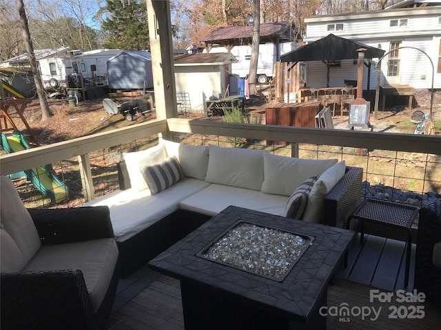 wooden terrace with an outbuilding, a storage shed, a playground, and an outdoor living space with a fire pit