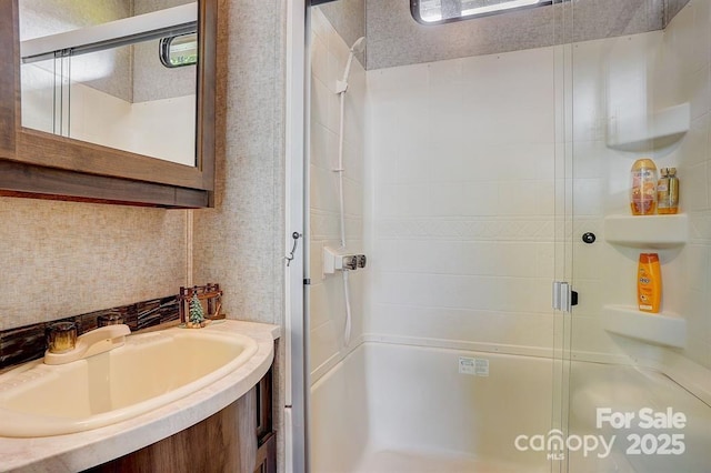 full bathroom with a stall shower, a sink, and wallpapered walls